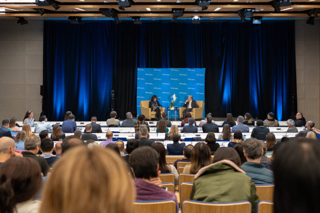 A large audience in a lecture hall at UCLA Samueli School of Engineering watches as Dean Alissa Park and UCLA Chancellor Julio Frenk sit on stage, facing each other, with the school's logo displayed in the backdrop.