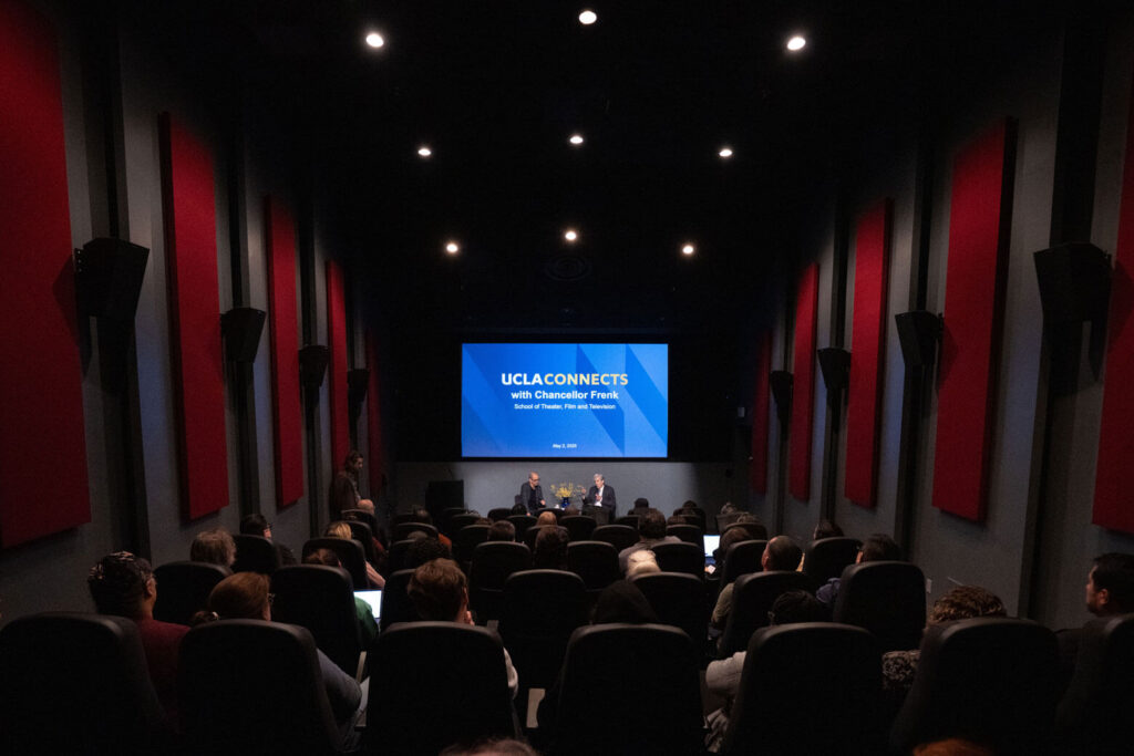 UCLA Chancellor Frenk sitting in a theater talking to audience with UCLA Connects projected on the screen.