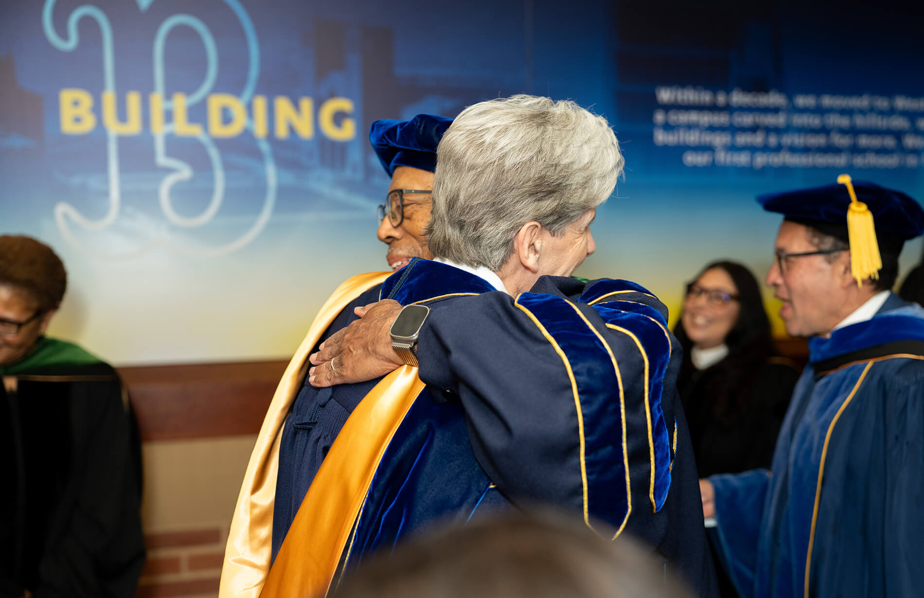 Chancellor Frank and UC President Drake wearing full regalia hug