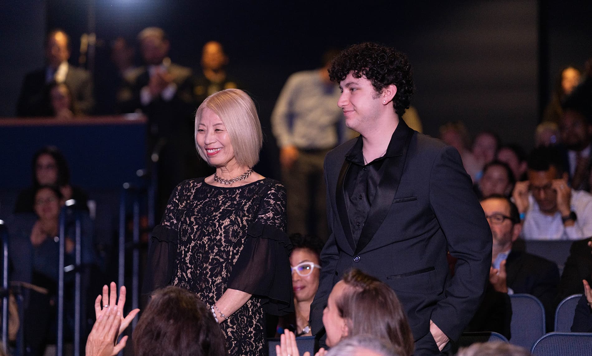 Two attendees walking through a crowd during a formal event.