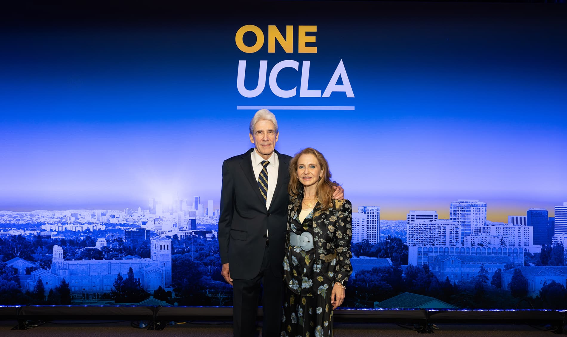 UCLA Chancellor Julio Frenk standing next to Felicia Knaul in front of a One UCLA backdrop.
