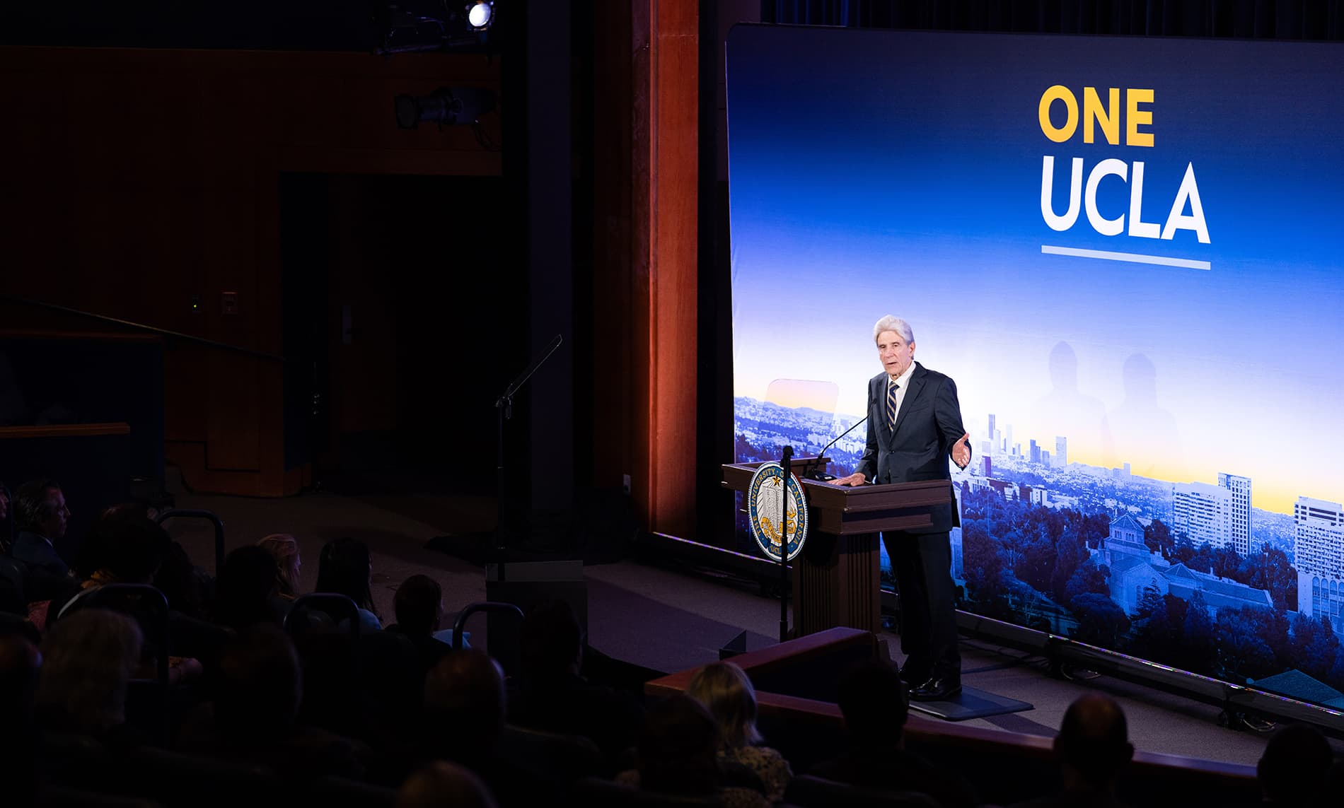 UCLA Chancellor Julio Frenk stands at a podium bearing the University of California seal.