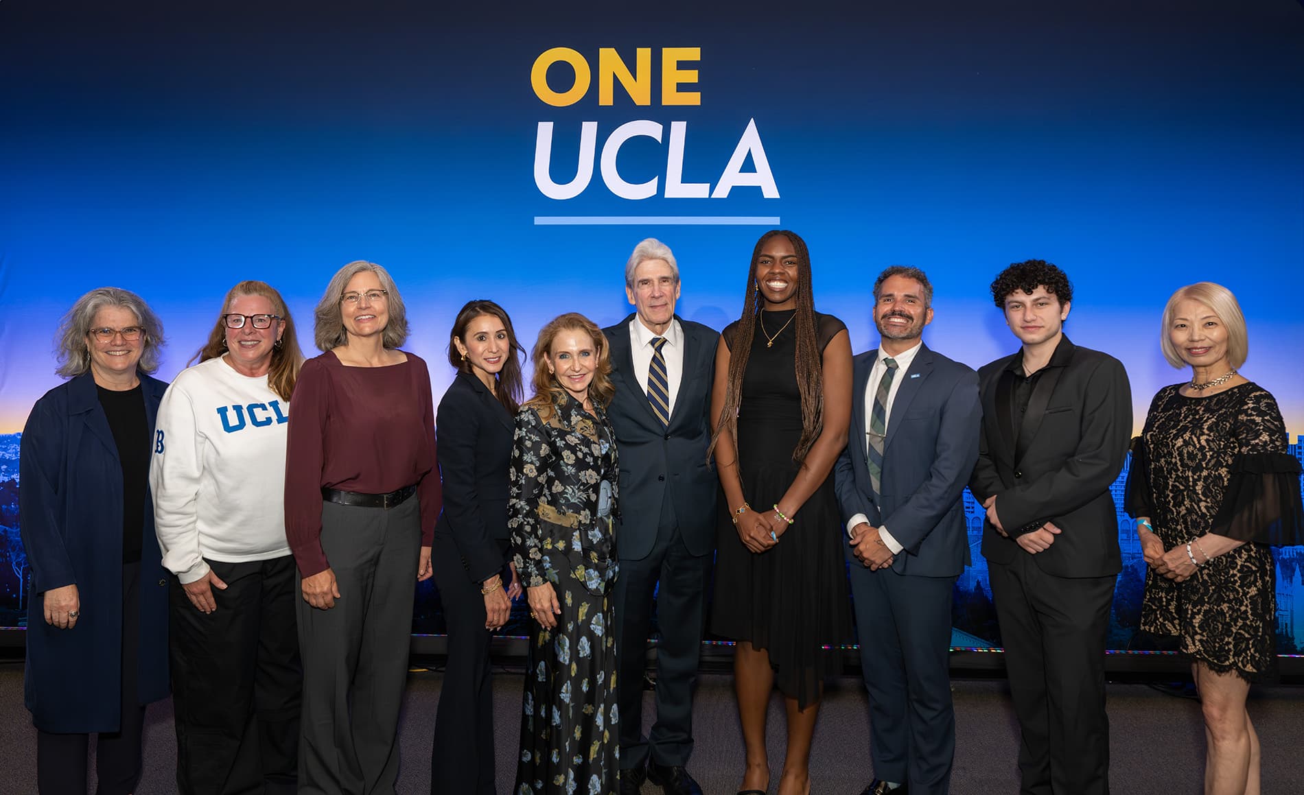 UCLA Chancellor Julio Frenk standing with a group of people in front of a One UCLA backdrop