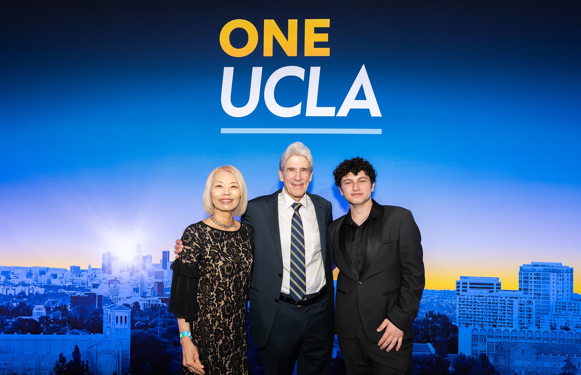 UCLA Chancellor Julio Frenk standing with two others in front of a One UCLA backdrop.
